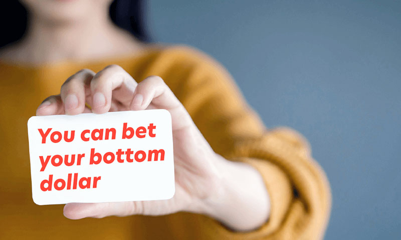 woman holding white card with poker term you can bet your bottom dollar in red text